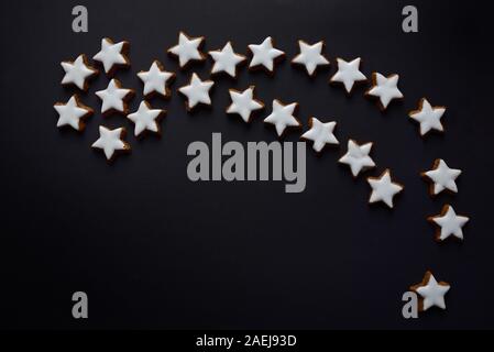 A big Christmas star made of many little biscuits in star shape, against a dark background with space for text Stock Photo