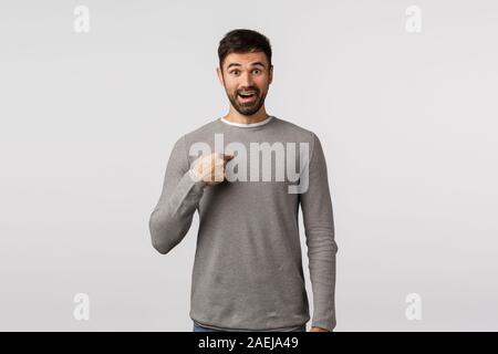 Who me, really. Surprised and happy young man being chosen and pointing himself with amazed smile, feeling grateful and relieved was picked Stock Photo