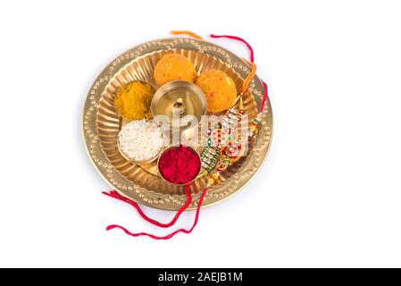 Indian Festival: Rakhi with rice grains, kumkum, sweets and diya on plate with an elegant Rakhi. A traditional Indian wrist band which is a symbol of Stock Photo