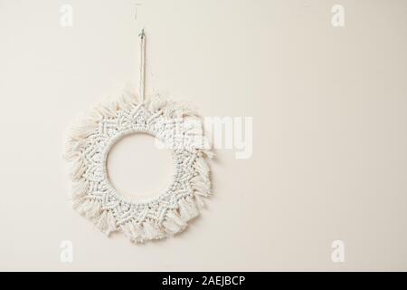 Handmade cotton macrame mandala wall decoration hanging on a wall with empty space Stock Photo