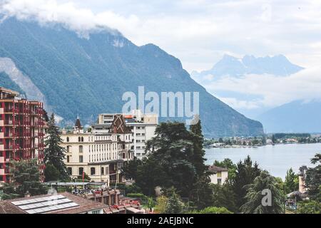 Cityscape of famous Montreux in Switzerland on a foggy day. Buildings by beautiful Lake Geneva, Swiss Alps in the background. Popular tourist destination, Swiss Riviera. Stock Photo