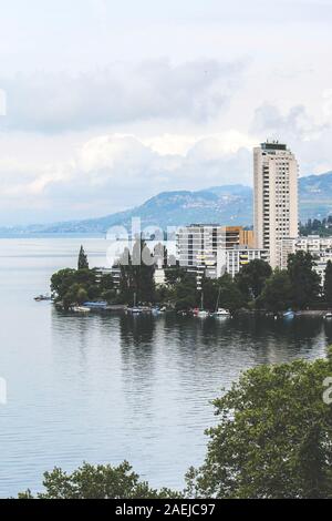 Cityscape of famous Montreux in Switzerland on a foggy day. Buildings by beautiful Lake Geneva. Popular tourist destination, Swiss Riviera. Vertical picture. Stock Photo