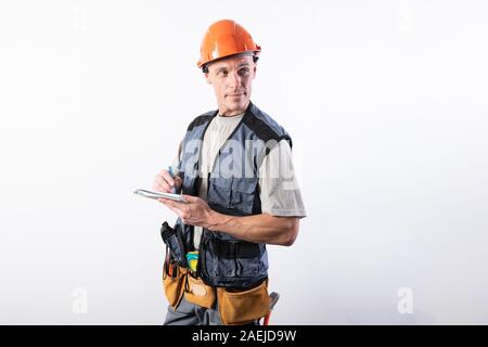 Builder with a notepad. In a helmet and a robe. Writes data. Stock Photo