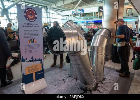 Heathrow Elf Squad in Heathrow Airport, Terminal 5, London. The ends of the tubes contain eyepieces to watch a 3D film of Christmas elves at work, Stock Photo