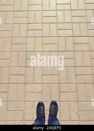 Legs in black leather shoes on the tiled floor of the sidewalk. Stock Photo