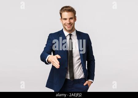 Entrepreneur, business and corporate concept. Attractive confident, smiling young blond businessman, extend arm for handshake say nice to meet you Stock Photo