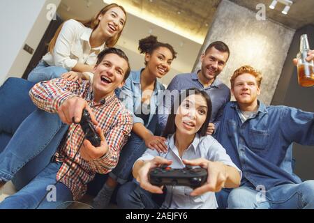 Group of friends having party indoors fun together playing battle game on console Stock Photo
