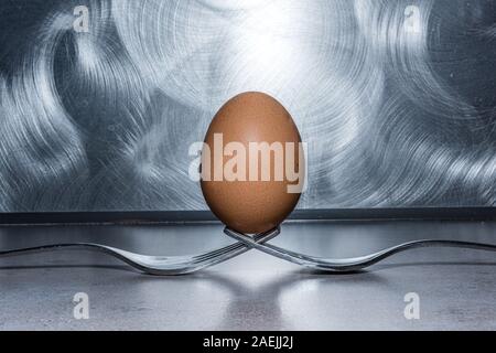 egg on two forks against stainless steel brushed background Stock Photo