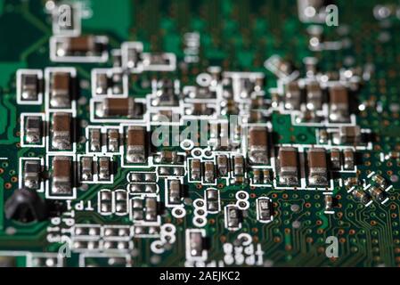 Detailed view of electronic components on a green printed circuit board used in modern electronic devices Stock Photo