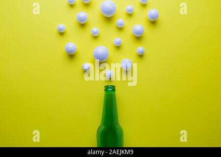 Beer abstract made of green bottle and styrofoam balls on yellow. Stock Photo