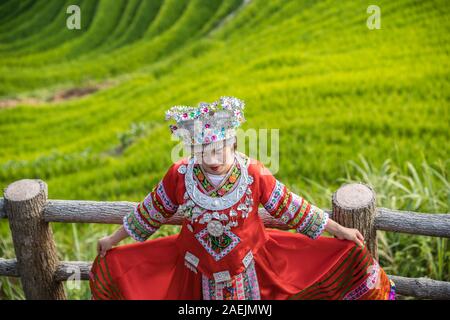 Pingan, China -  August 2019 : Chinese woman dressed in traditional decorated red folk costume posing for photos on a Nine Dragons and Five tigers vie Stock Photo