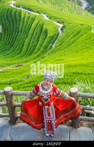 Pingan, China -  August 2019 : Chinese woman dressed in traditional decorated red folk costume posing for photos on a Nine Dragons and Five tigers vie Stock Photo