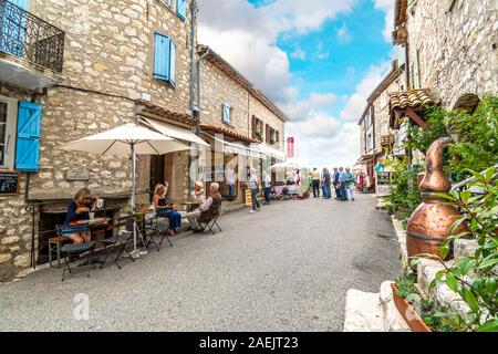 Tourists sit at an outdoor sidewalk cafe in the medieval hilltop village of Gourdon in the Provence Alpes Maritimes area of Southern France. Stock Photo