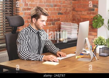 Man working with computer at office. Serious young businessman or employee Stock Photo