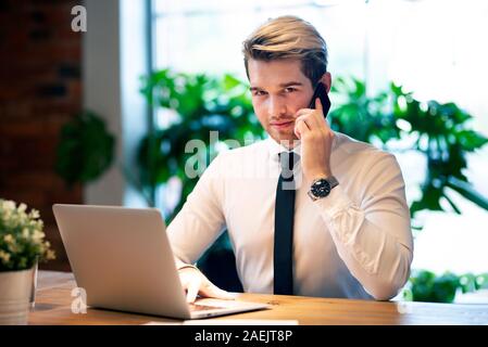 Businessman working in office. Handsome employee talking on the phone. Stock Photo