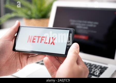 Wroclaw, Poland - OCT 23, 2019: Man with Netflix logo on screen. Netflix is most popular video streaming platform. Stock Photo