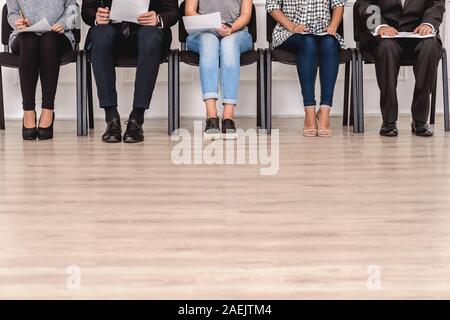 Job Interview. Candidates sitting waiting with resumes floor and legs close-up Stock Photo