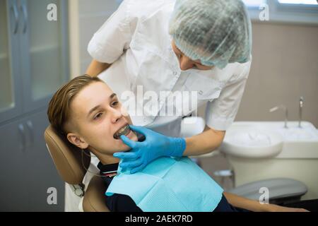 Woman dentist puts on a guy patient a mouth guard (a removable orthodontic teeth alignment and correction trainer appliance) in dental office. Stock Photo