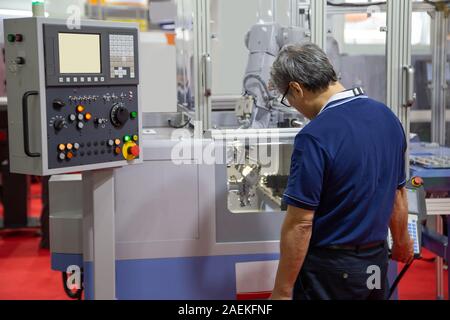 Worker control compact CNC lathe with robotic loading workpiece Stock Photo