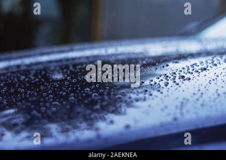 Water drops on the surface of a blue car in cold colors Stock Photo