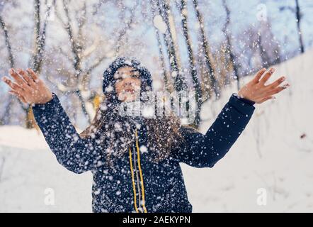 Winter portrait of young beautiful woman wearing knitted snood covered in snow. Snowing winter beauty fashion concept Stock Photo