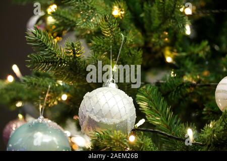 Christmas tree decorated with blue and white baubles. Artificial fir tree with led light garland. Festive holiday background. Stock Photo