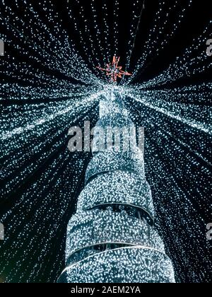 new year tree made of white led lights with red star on top and garlands lights hanging from the starr. vertical view Stock Photo