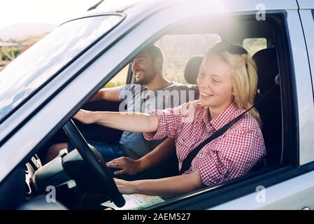 Happy couple traveling by car in nature. Carefree friend travelers on countryside roadtrip journey. Young woman and man driving on romantic weekend.