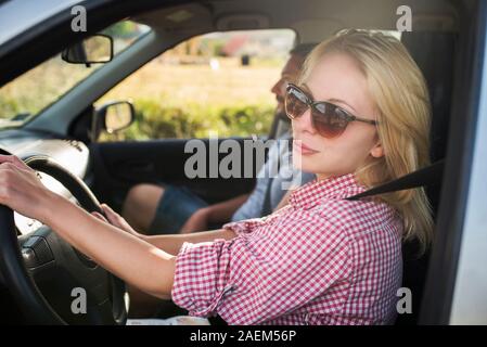 Happy couple traveling by car in nature. Carefree friend travelers on countryside roadtrip journey. Young woman and man driving on romantic weekend. Stock Photo