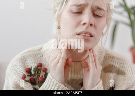 The girl in the sweater is sick. Colds and flu. The patient caught a cold, feeling sick. Unhealthy girl with a sore throat. Stock Photo