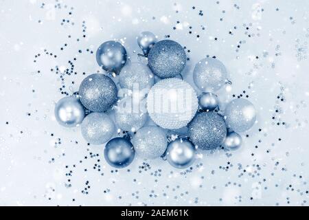 New Year or Christmas pattern flat lay top view Xmas holiday celebration pearl decorative toy balls sparkles confetti blue paper background with snow. Stock Photo