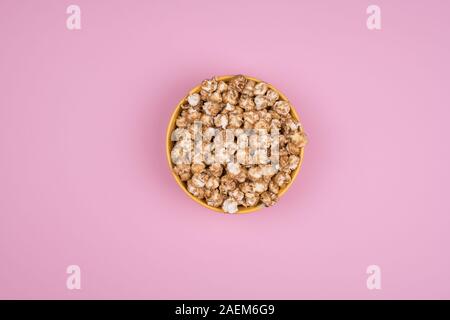 Caramel sweet popcorn bowl isolated on pink background top view. Frame composition with copy space. Stock Photo