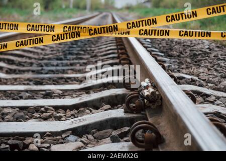 Be aware. Dangerous explosive lying on the railway. Yellow caution tape in front Stock Photo