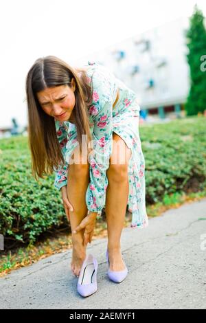 Elegant woman feeling foot ache, wearing small shoes or using high heel for long time Stock Photo