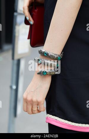 MILAN, ITALY - SEPTEMBER 22, 2019: Woman with silver snake bracelet with green gems before Gucci fashion show, Milan Fashion Week street style Stock Photo