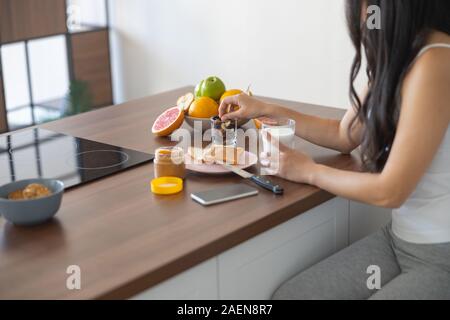 Young Asian woman eating her breakfast indoors Stock Photo