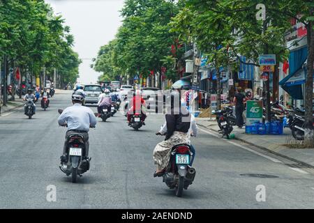 Motorcycle riders and cars driving the streets of the city Hue in Vietnam on May 2, 2019 Stock Photo