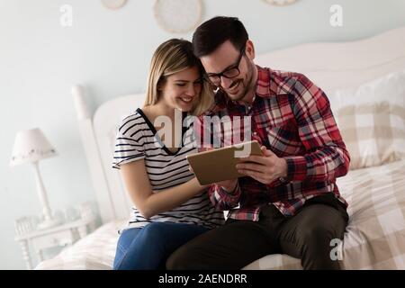 Young attractive couple using tablet in bedroom Stock Photo