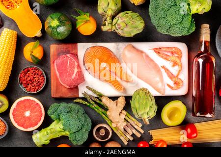 Food variety, a flat lay composition with meat, fish, chicken and shrimps, vegetables and fruits, wine and pasta, shot from the top on black Stock Photo