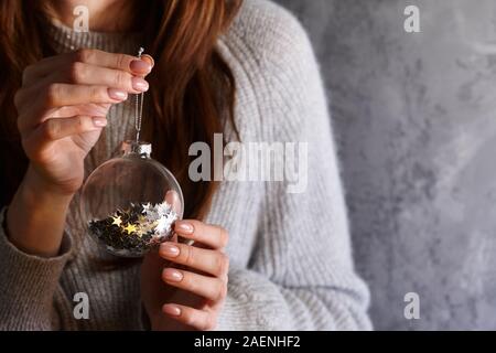 Woman holding Christmas glass ball with glistening star pailettes inside, holiday concept Stock Photo