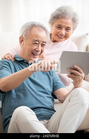 Happy senior couple using digital tablet in living room Stock Photo