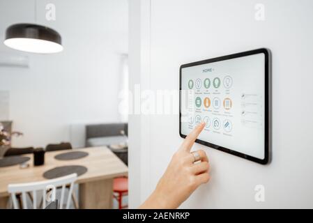 Controlling home with a digital touch screen panel installed on the wall. Close-up on a screen with mobile application for managing smart devices Stock Photo
