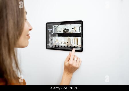 Young woman watching video from security cameras on a digital tablet at home. Concept of remote video surveillance over the internet with smart devices Stock Photo