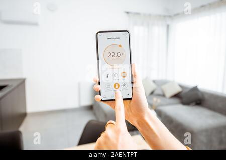 Controlling home heating temperature with a smart home, close-up on phone. Concept of a smart home and mobile application for managing smart devices at home Stock Photo