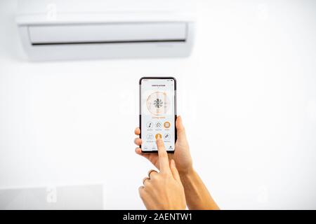 Controlling home conditioning with a smart phone, close-up. Concept of a smart home and mobile application for managing smart devices at home Stock Photo