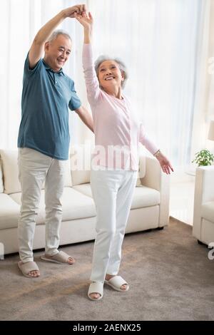 Happy senior couple dancing in living room Stock Photo