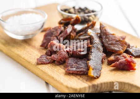 Beef jerky pieces. Dried beef meat on cutting board. Stock Photo