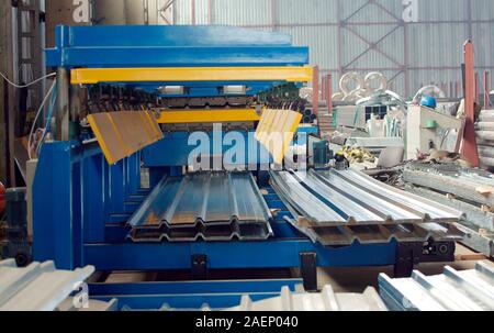 The industrial device for corrugated metal sheets bending by high precision machine in factory. Blue line machine conveyor for cutting sheet metal in Stock Photo