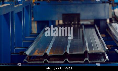 The industrial device for corrugated metal sheets bending by high precision machine in factory. Blue line machine conveyor for cutting sheet metal in Stock Photo