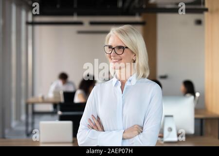 Smiling mature businesswoman dreaming in office, business vision concept Stock Photo